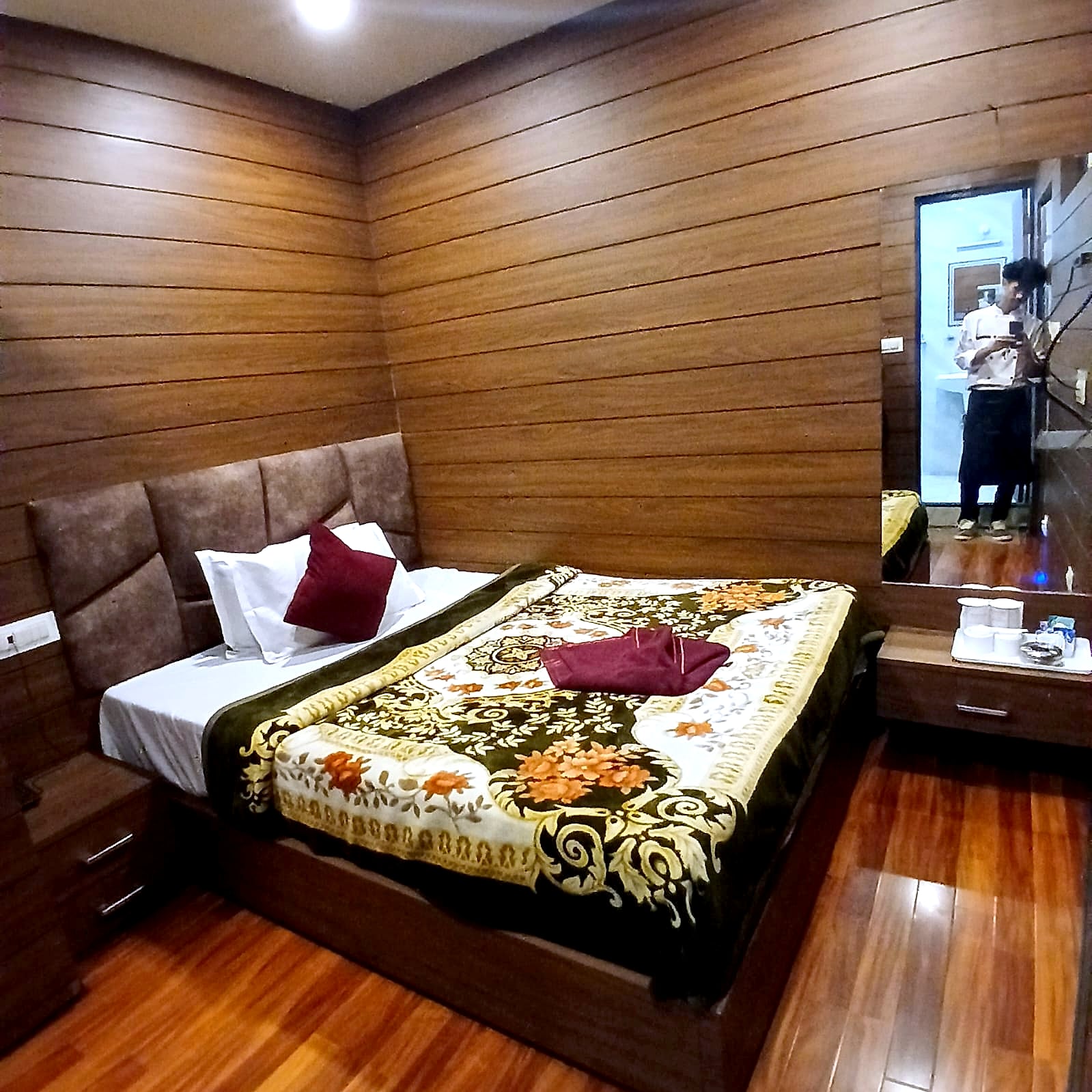 A wood-panelled double room at Hotel Charlie with a mirror and bedside table