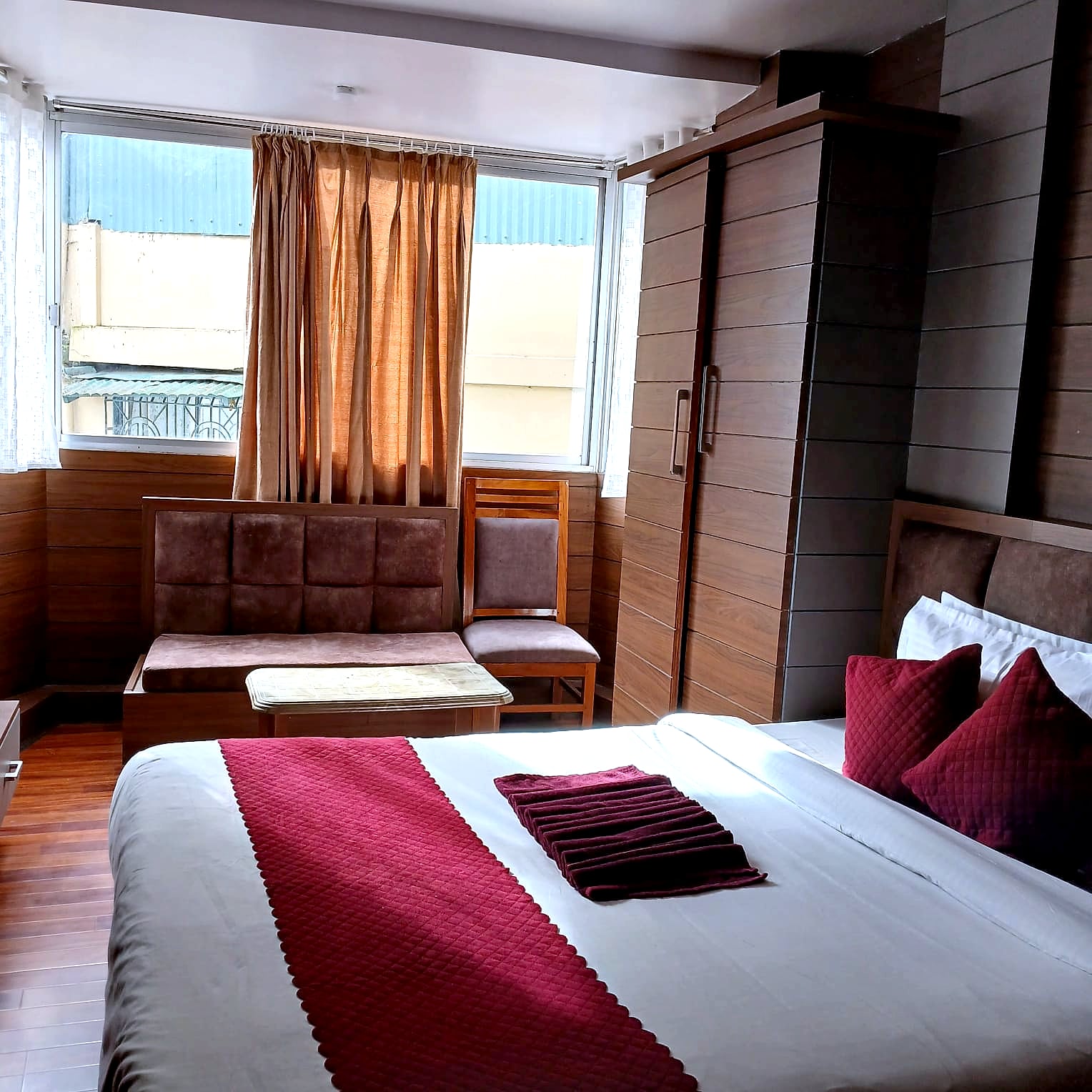 A newly renovated room at Hotel Charlie with a double bed, a sofa seating corner and wood-panelled walls